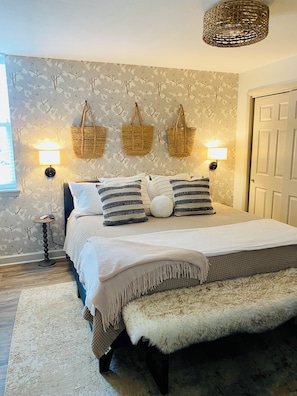 Une chambre à coucher avec un lit, des lampes de chevet, un panier fixé au mur et une porte.