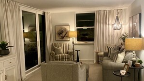 Un salon avec un canapé, un fauteuil et une petite table sur laquelle se trouve une lampe.