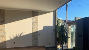 Un intérieur moderne avec des murs en pierre, un palmier et une vue dégagée sur l’extérieur.