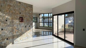 Un intérieur spacieux avec un mur en pierre, de grandes fenêtres et un sol réfléchissant.