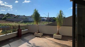 Un balcon agrémenté de plantes en pot, une vue dégagée sur le quartier et un immeuble en arrière-plan.
