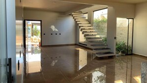 Un intérieur moderne avec un plancher poli, un escalier en colimaçon et une porte en verre donnant sur l’extérieur.