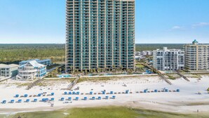Un hôtel de grande hauteur offrant une vue sur la plage, doté de nombreux balcons et d’un espace piscine.