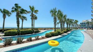 Une piscine avec un flotteur jaune en forme de cercle, entourée de palmiers et offrant une vue sur la plage.