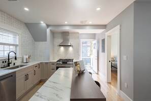 A modern kitchen with a marble countertop, stainless steel appliances, and a large island. - Stunning 4BR2BA w Parking/Near Downtown/ +Parking (Boston)