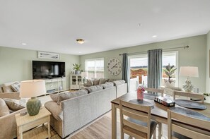 Ein Wohnzimmer mit Sofa, Fernseher, Esstisch und Stühlen.