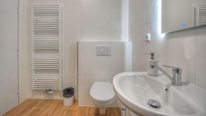 A bathroom with a toilet, sink, mirror, and towel rack.