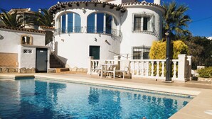 A poolside view of a white building with a balcony, a door, and a staircase leading to the entrance. - Villa Mitica with Private Pool in Benitachell (El Poble Nou de Benitatxell/Benitachell)