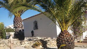 A building with a stone wall, a palm tree, and a statue in a garden area. - Villa Mitica with Private Pool in Benitachell (El Poble Nou de Benitatxell/Benitachell)