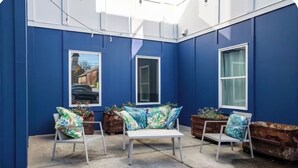 A blue-painted room with a white bench, two chairs, and potted plants.