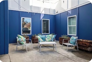 A blue-painted room with a white bench, two chairs, and potted plants.