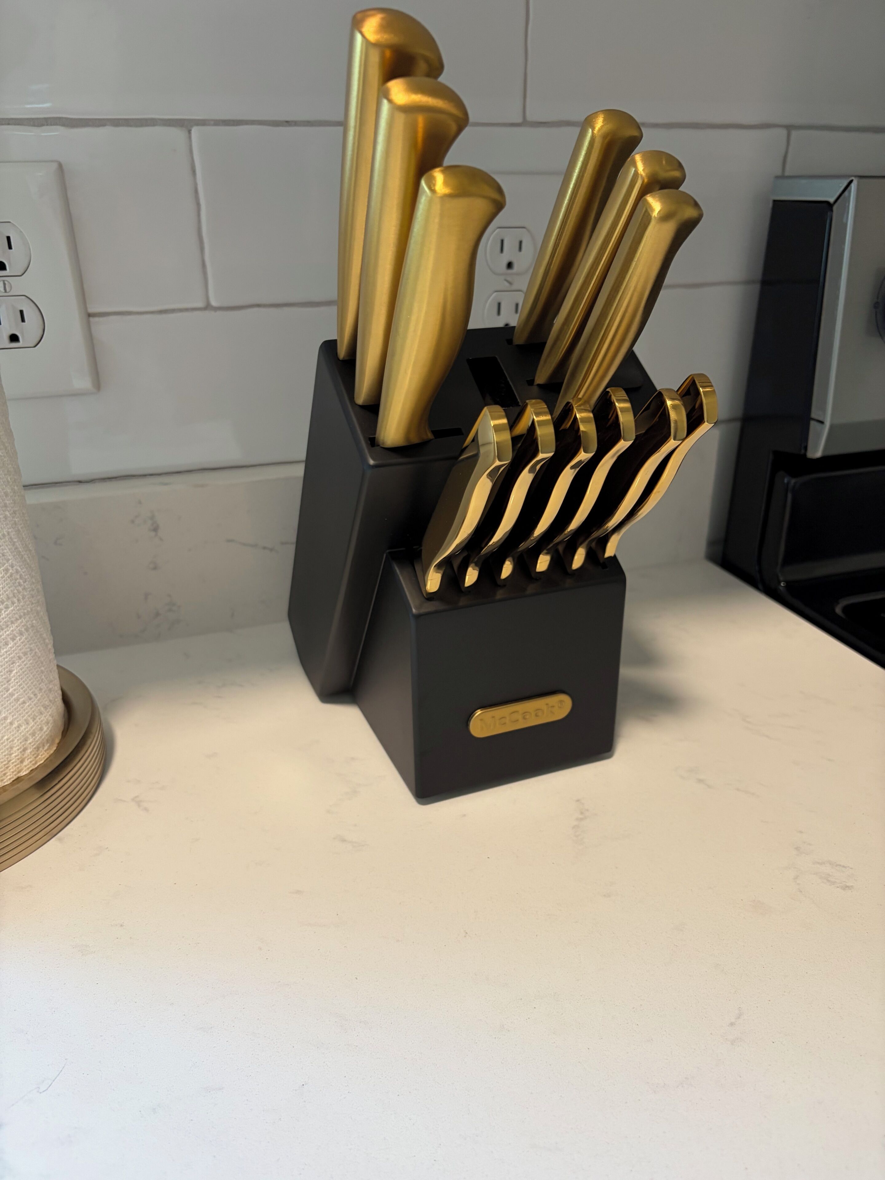 A kitchen counter with a knife block containing several knives.