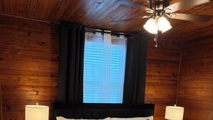 A wooden-paneled bedroom with a bed, two bedside lamps, a ceiling fan, and a window with blinds. - The Corner 82 /High End Nature Escape King beds (Winder)