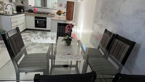A modern kitchen with white cabinets, a dining table with chairs, and a view into the living area. - Cozy apartment in Belém, close to the main tourist attractions. (Belém)