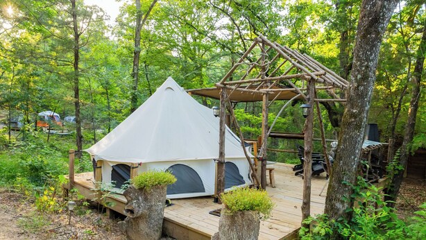 Una carpa con una terraza de madera y una jardinera de tocón.