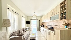 Ett modernt kök med träskåp, en matplats med en soffa och en tv.
