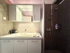 Un baño moderno con lavamanos, espejo y ducha.