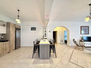 A spacious kitchen with a central island, modern appliances, and a dining area with chairs. - Villa Fenia (Amorgos)
