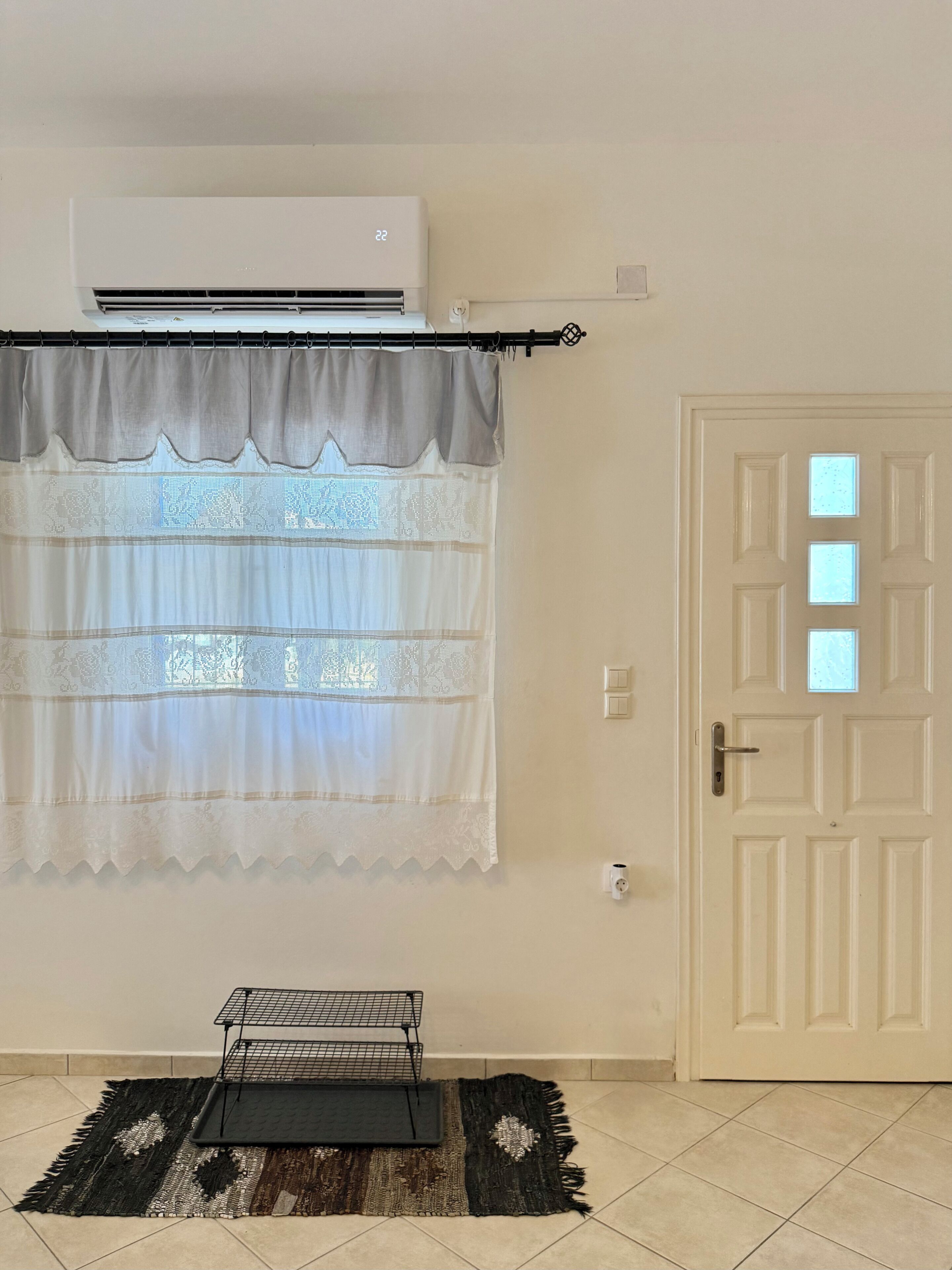 Ein Zimmer mit Fenster, Klimaanlage, Tür und einem kleinen Tisch mit Tablett.