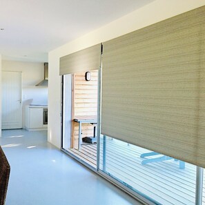 A modern interior with a sliding glass door, a kitchen area, and a white door. - Holiday home, !natural park, nearby Ocean, Forest, Lake (Messanges)