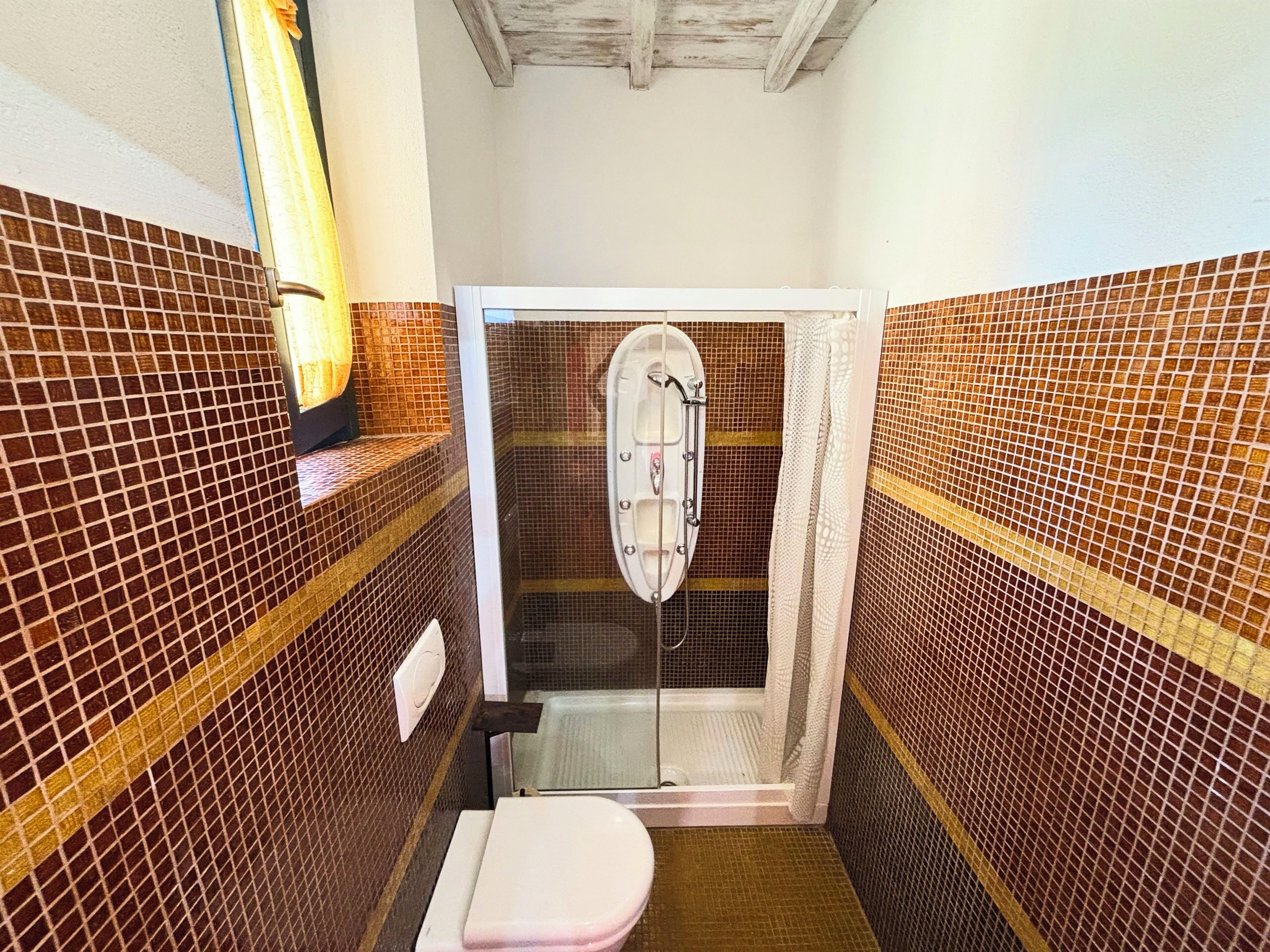 Un baño con cabina de ducha, inodoro y paredes con azulejos.