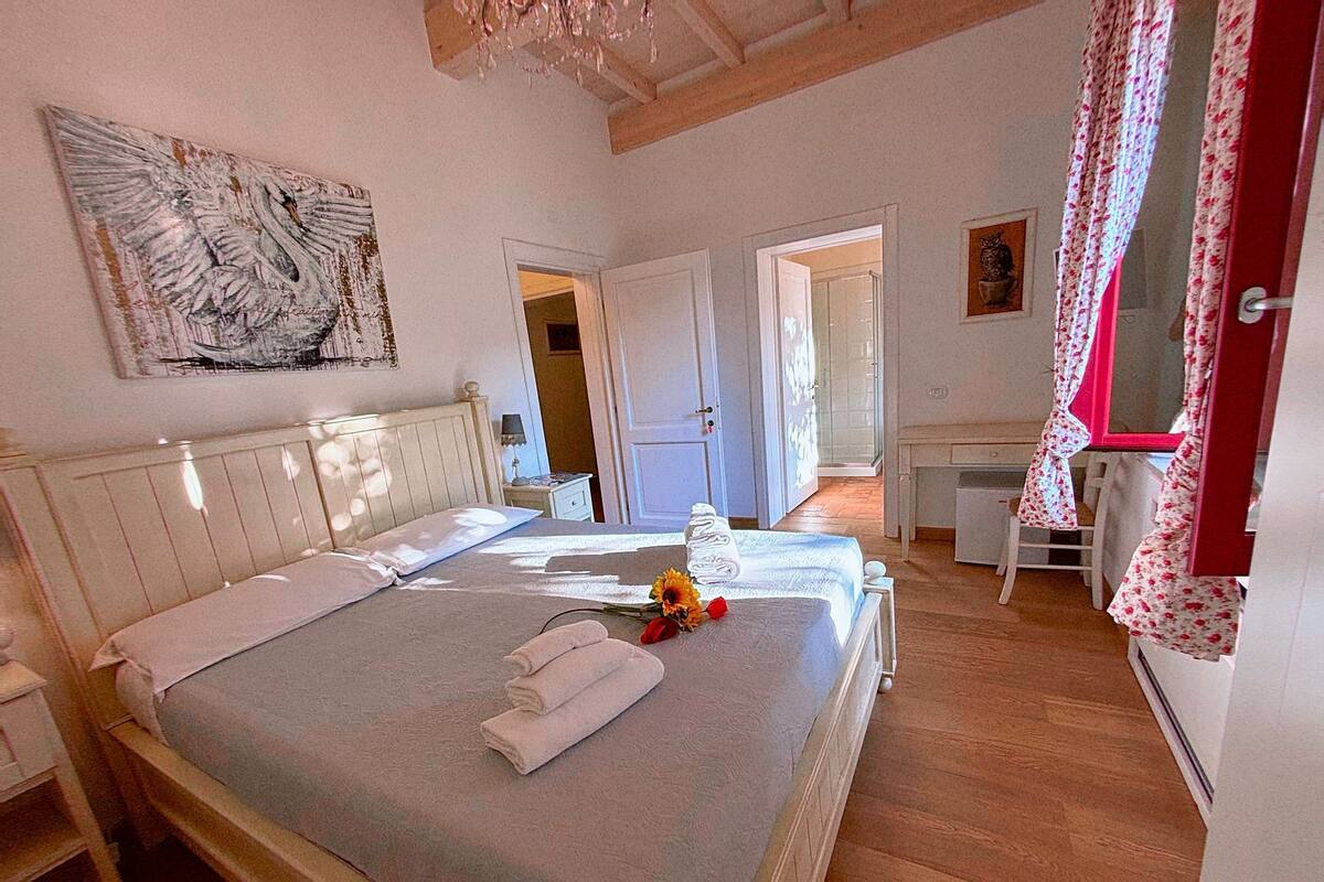 A bedroom with a large bed, a desk, and a shower area.