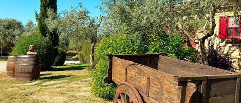 An outdoor scene with a wooden cart, barrels, and a building with red shutters.