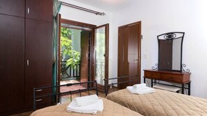 Un dormitorio con dos camas, un armario de madera, un espejo y vistas a zonas verdes.