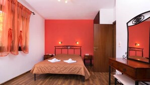 Ein Zimmer mit einem Bett, einem Holzschrank, einem Spiegel und einer roten Wand.