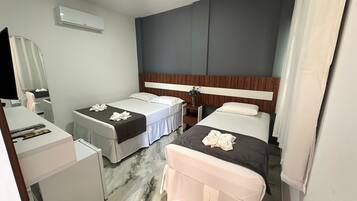 Et hotelværelse med to senge, et skrivebord, en stol, et spejl og en aircondition.