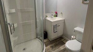 A bathroom with a glass-enclosed shower, a white sink, and a toilet. - Hidden Gem 💎 Stylish Suite w/ All-Inclusive Comfort” (Regina)