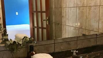 A bathroom with a sink, a mirror, and a door leading to a room with a blue wall.
