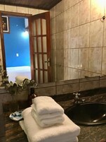 A bathroom with a sink, a mirror, and a door leading to a room with a blue wall.
