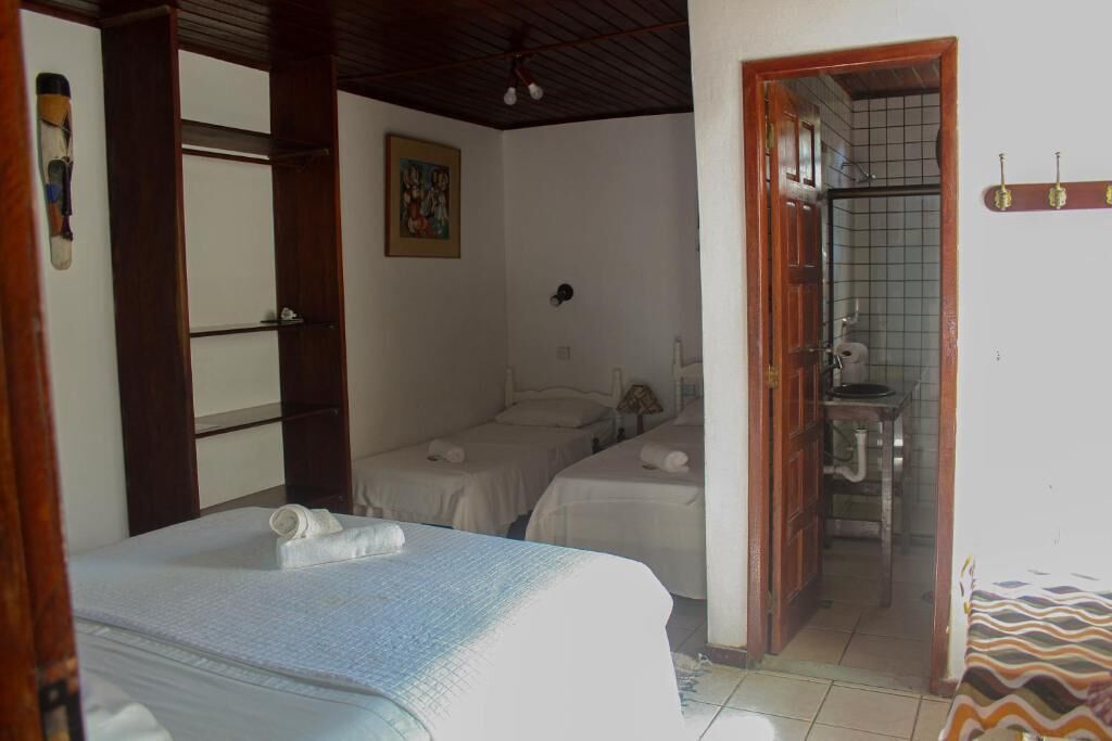 Una habitación con dos camas, baño y una pequeña cocina.
