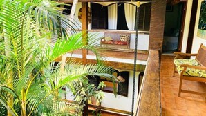 A multi-level building with balconies, a wooden bench, and potted plants. - Pousada Tropicana (Angra dos Reis)