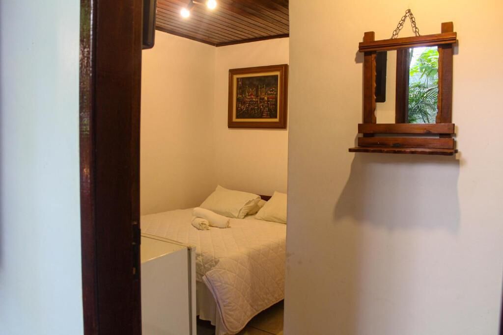 Ein Schlafzimmer mit einem Bett, einem Bild an der Wand und einem kleinen Fenster mit Blick auf Grünflächen.