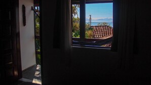 A doorway leading to a balcony with a view of a tiled roof and a distant mountain. - Pousada Tropicana (Angra dos Reis)