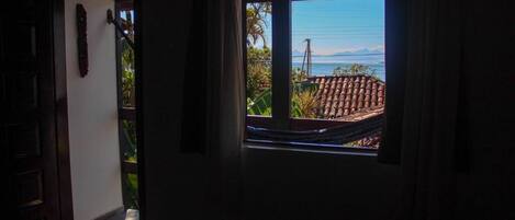 A doorway leading to a balcony with a view of a tiled roof and a distant mountain.