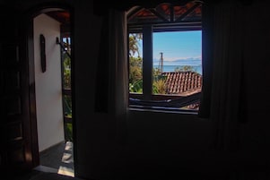 Una puerta que da a un balcón con vistas a un tejado de tejas y una montaña lejana.