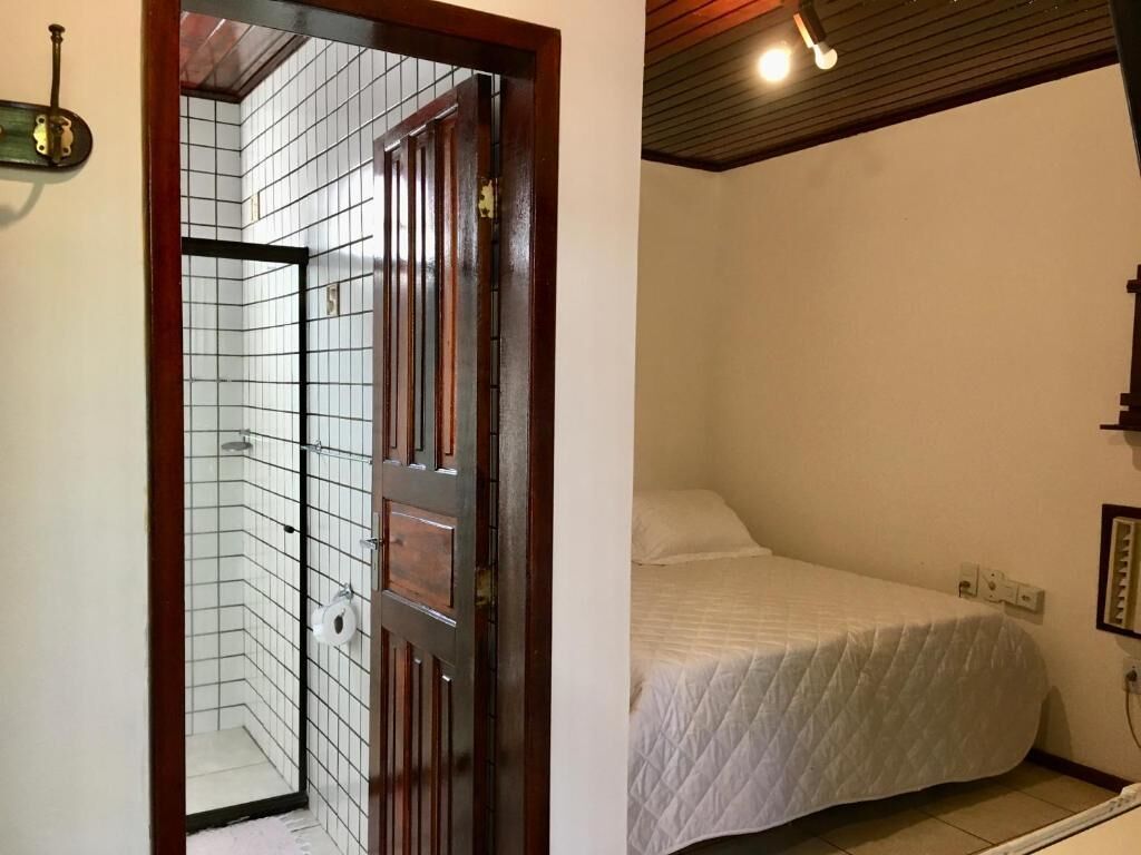 A bedroom with a bed, a wooden door, and a tiled shower area.