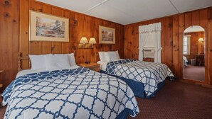 Una habitación con paneles de madera, dos camas con ropa de cama estampada, lámparas fijadas a la pared y cuadros enmarcados.