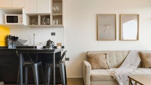 Een moderne keuken met een magnetron, barstoelen en een koffiezetapparaat.