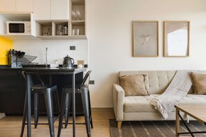 A modern kitchen with a microwave, bar stools, and a coffee maker. - Modern Apartment in Nunoa Terrace and Pool (Ñuñoa)