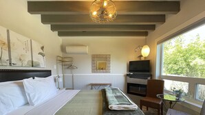 Een hotelkamer met een bed, een televisie, een open haard en een raam met uitzicht op bomen.