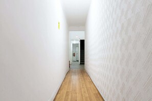 A narrow hallway with wooden flooring and white walls, leading to a door at the end. - Cosy 1BDR Studio Flat Perfect for Exploring London (Greater London)