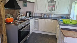 Uma cozinha com armários brancos, fogão, forno, pia e cafeteira.