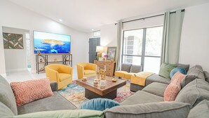 Ein Wohnzimmer mit einer Couch, Sesseln, einem Couchtisch und einem Fernseher.