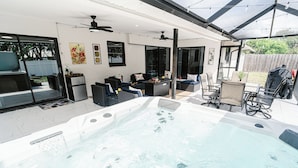 Ein Whirlpool mit Sitzgelegenheiten und Deckenventilator, ein Grill und ein durch einen Zaun gesicherter Garten.