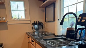 A kitchen with wooden cabinets, a countertop, a window, and a coffee maker.