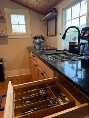 A kitchen with wooden cabinets, a countertop, a window, and a coffee maker.